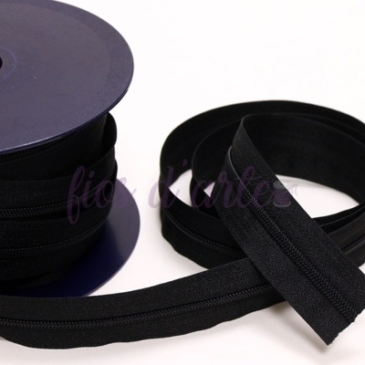 Rolo e tira de fecho éclair preto num fundo branco