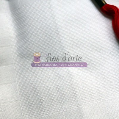 Tecido branco quadriculado com novelo de linha vermelha e etiqueta com texto