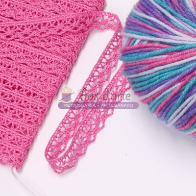 Novelo de lã colorida azul, rosa e branco com tecido rosa em malha fina ao lado