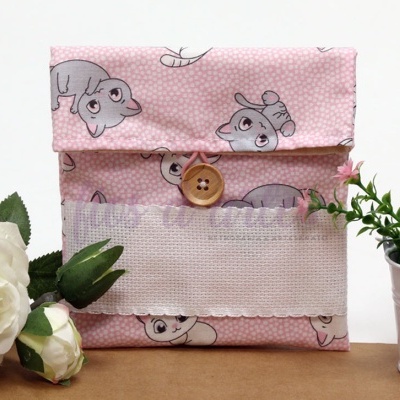 Bolsa rosa com padrão de gatos e botão de madeira entre flores artificiais