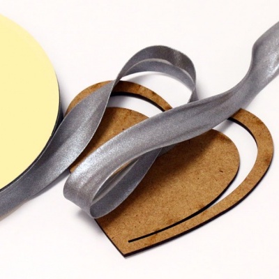 Fita prateada em cetim sobre fundo branco com coração de cartão e círculo amarelo