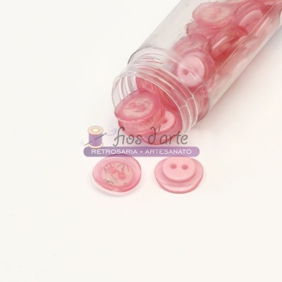 Frasco de botões cor-de-rosa de plástico transparente aberto com botões fora do frasco