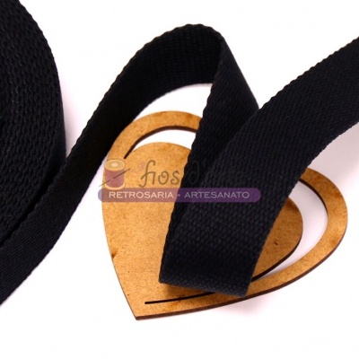 Fita de tecido preta sobre cartão em forma de coração com etiqueta roxa.