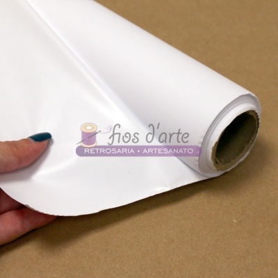 Rolo de tecido branco liso segurado por mão sobre superfície castanha