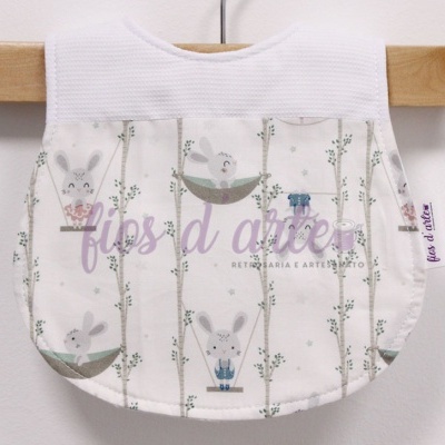 Babete com padrão de coelhos e folhas verdes em fundo branco