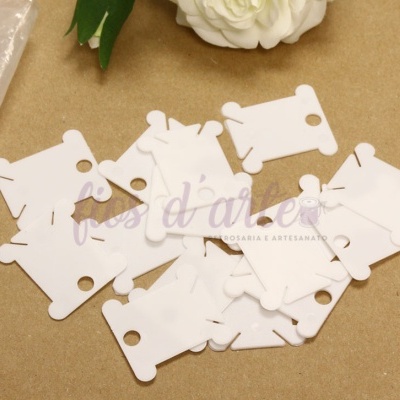 Placas brancas de plástico com recortes sobre mesa castanha com flor branca e texto de fundo