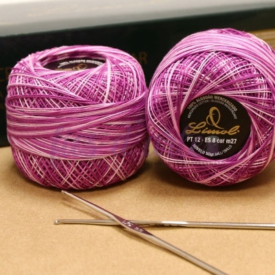 Novelos de linha roxa com agulhas de croché prateadas