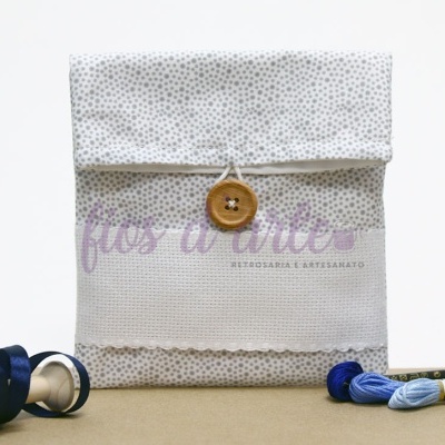 Envelope de tecido branco com pontos cinza e botão de fecho em madeira