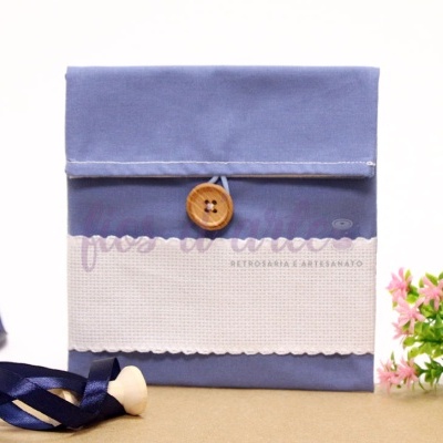 Bolsa de tecido azul com botão de madeira e flores rosas ao lado