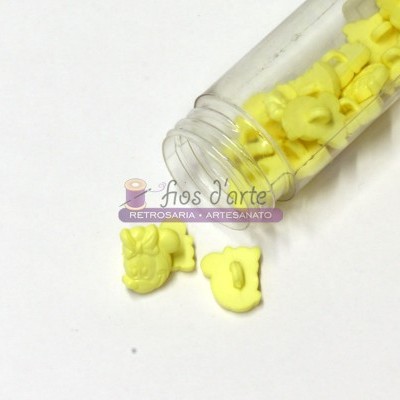 Frasco aberto com botões amarelos em formas diversas sobre fundo branco