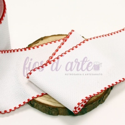 Fita branca de tecido com bordas vermelhas costuradas sobre madeira rústica