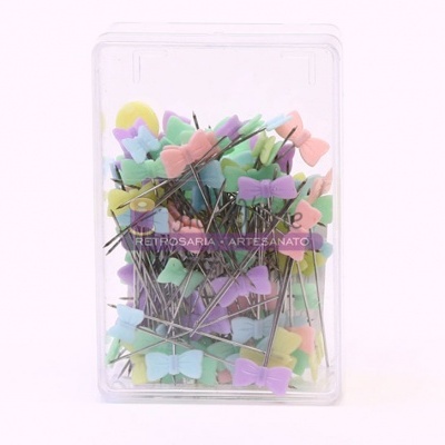 Caixa transparente com alfinetes de cabeça em forma de laço coloridos.