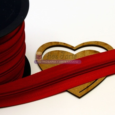 Bobina de fita vermelha com texto 'RETROSARIA - ARTESANATO' em coração de madeira