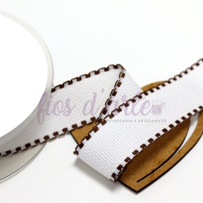 Fita branca de tecido com bordas castanhas enrolada num carretel