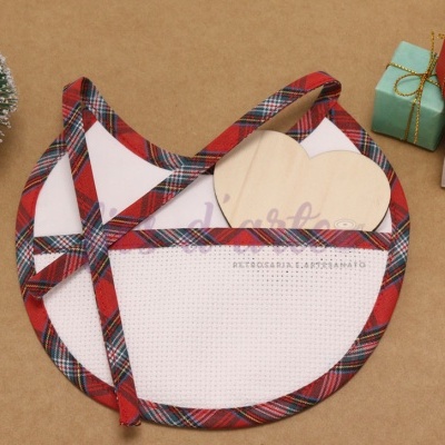 Avental branco com bordas e alças em tecido xadrez vermelho, verde e branco, com uma pequena árvore de Natal e presentes coloridos ao lado.