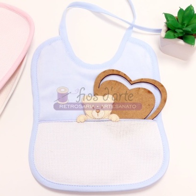 Babete de bebé branco com borda azul e bolso em malha, porta-chaves em forma de coração em madeira e planta artificial