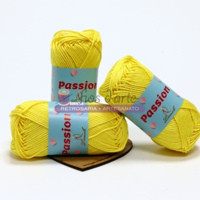 Três novelos de fio amarelo com etiquetas azuis e texto vermelho