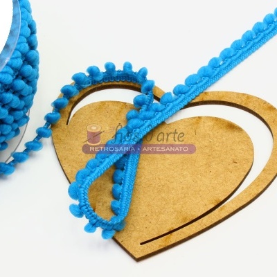 Fita azul com pompons sobre base de madeira em forma de coração