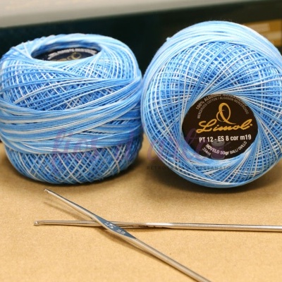 Dois novelos de linha azul claro com agulha de crochê e rótulo