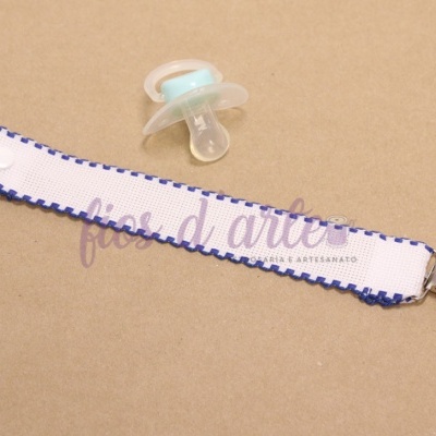 Clipe para chupeta com fita branca e bordas azuis, fecho de coração e chupeta azul e transparente