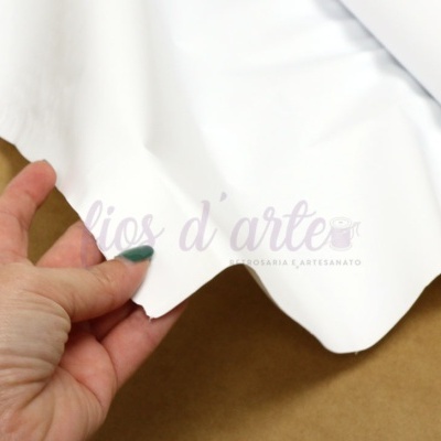 Pano branco com texto quase transparente segurado por mão sobre superfície castanha