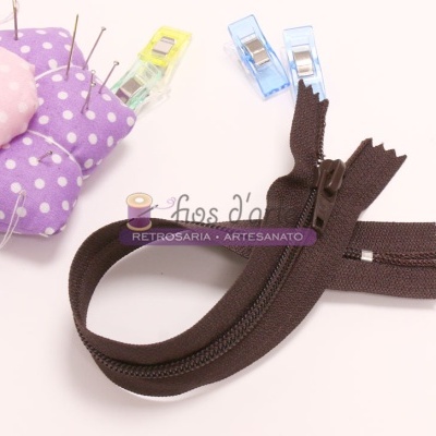 Fecho éclair castanho com cursor plástico e almofada de tecido roxo com bolinhas brancas