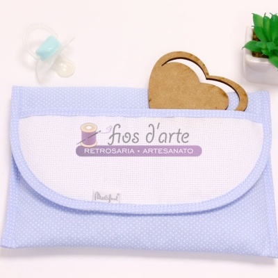 Bolsa de tecido azul claro com etiqueta Fios d'arte, chupeta, moldura de coração de madeira e planta suculenta