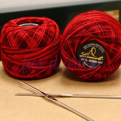 Novelos de fio vermelho de algodão com agulhas de crochet metálicas