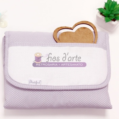 Bolsa lilás com padrão de pontos brancos e texto 'fios d'arte RETROSARIA • ARTESANATO' com vaso e coração de madeira