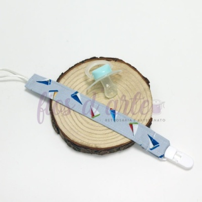 Chupeta azul clara com fita prendedor estampada e tronco de madeira como suporte