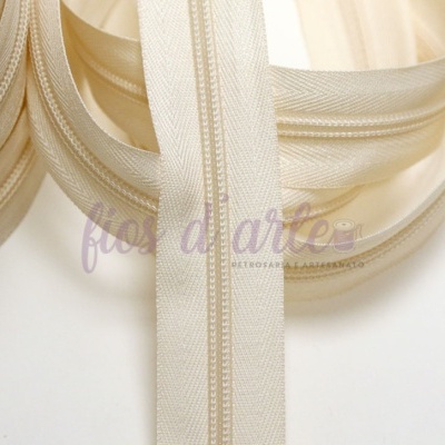 Fecho éclair bege claro com textura de tecido sintético sobre fundo branco