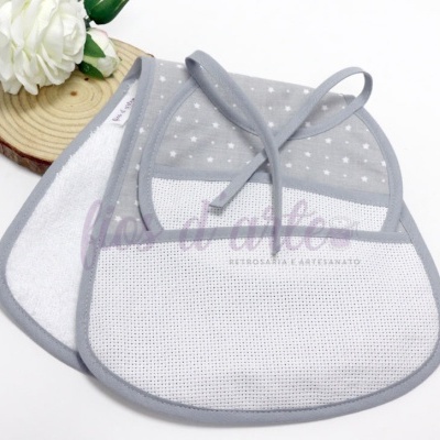 Dois babetes para bebé em tecido cinzento e branco com padrão de estrelas, junto a flor branca