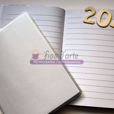 Caderno com capa prateada aberto, números de madeira 2017 ao lado e texto digital flos d'arte RETROSARIA • ARTESANATO