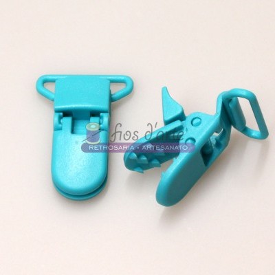 Prendedor de plástico azul turquesa com fecho em fundo branco e etiqueta de loja