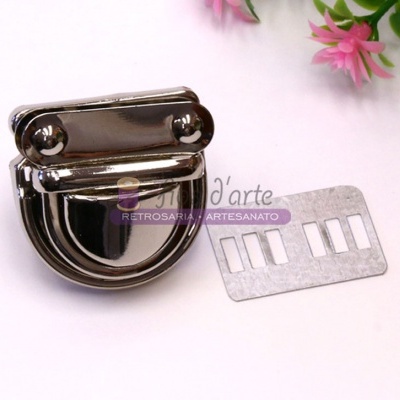 Fecho metálico prateado e peça metálica retangular sobre superfície branca com flores rosa