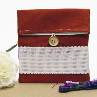 Estojo em tecido vermelho com botão de madeira e faixa bordada branca com padrão lilás