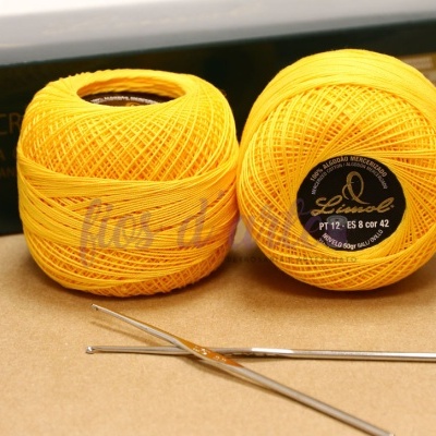 Novelos amarelos de linha para crochet e agulhas em superfície castanha