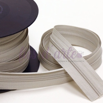 Rolo de fecho éclair bege claro com um fecho separado em fundo branco