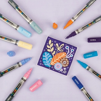 Marcadores de tinta LYRA coloridos dispostos em círculo sobre fundo lilás com desenho floral no centro