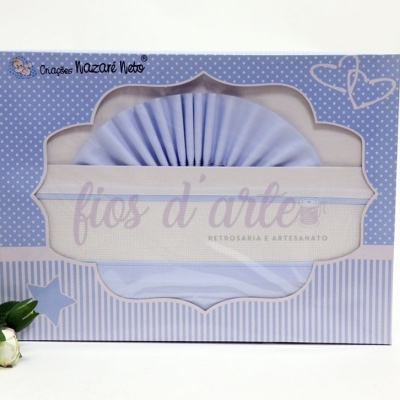 Embalagem azul com fios de arles, decorada com bolinhas, riscas e texto, com flores brancas ao lado