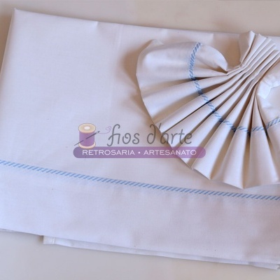 Toalha branca com linhas azuis dobrada em formato de leque