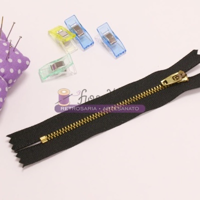 fecho éclair preto com dentes dourados, prendedores coloridos e almofada de alfinetes lilás