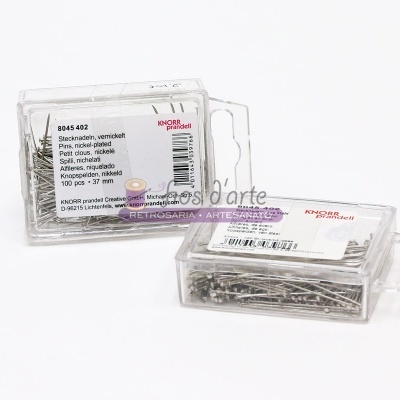 Duas caixas transparentes com alfinetes prateados de cabeça perolada e etiquetas com texto em alemão e inglês