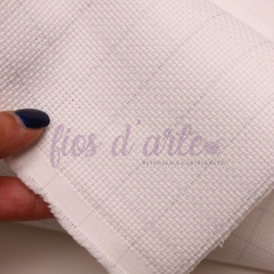 Tecido branco de algodão com padrão quadriculado segurado por mão com unhas azuis