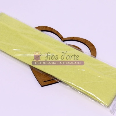 Faixa elástica amarela claro embalada em plástico com etiqueta sobre coração de madeira