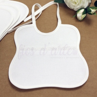 Babete branco de tecido com padrão de malha e flores artificiais em fundo castanho.