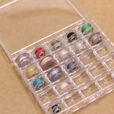 Caixa de plástico transparente com bobinas de linha coloridas separadas