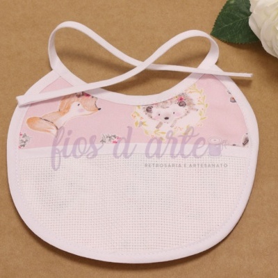 Babete rosa com estampado de animais e borda branca, com faixa para bordar, em fundo castanho com flores brancas