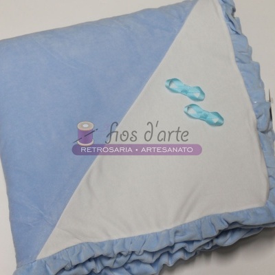 Colcha azul claro e branca dobrada com bordas franzidas e laços azuis pequenos