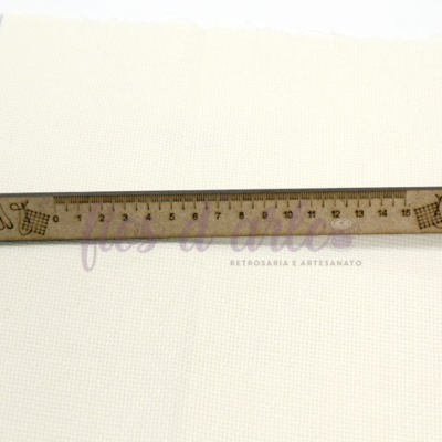 Régua de madeira com desenhos gravados sobre tecido branco texturizado